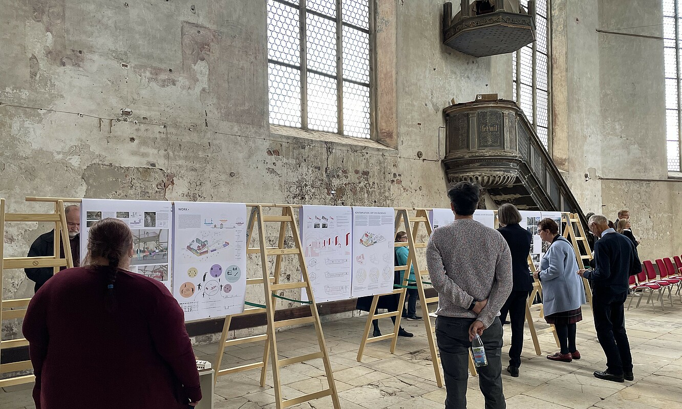 Besucherinnen und Besucher betrachten die Plakate der Studierenden in der Ausstellung.