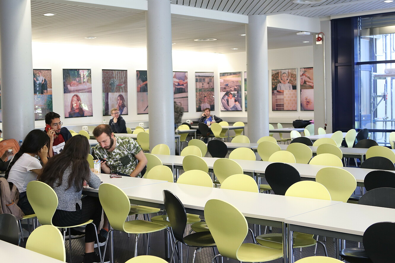 Students in the dining hall (Mensa) search for the right contact on their mobile phones